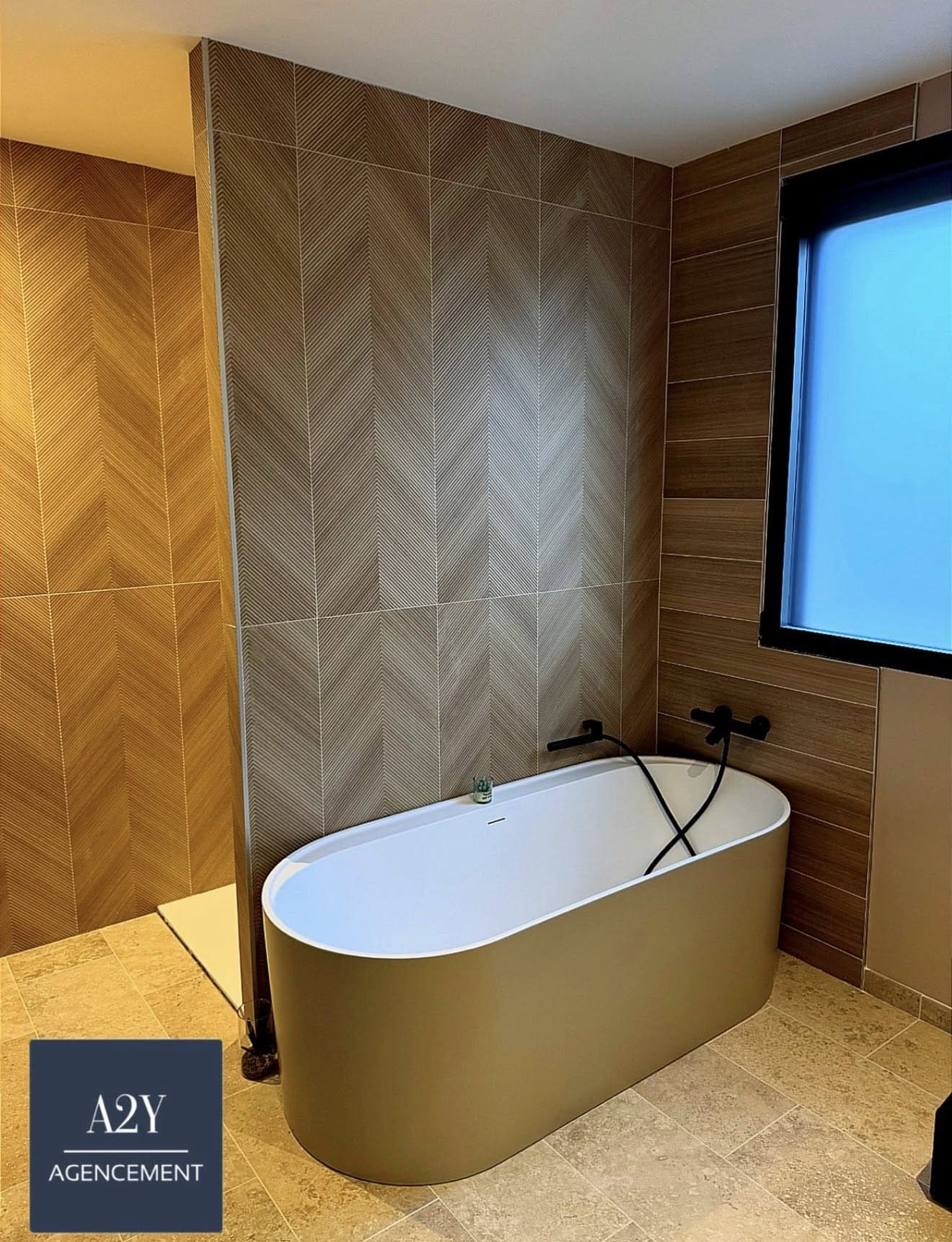 Salle de bain rénovée avec baignoire îlot et carrelage chevron — A2Y Agencement Loire 42